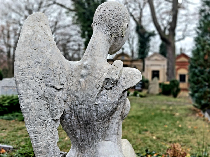 Ein Engel aus Stein steht auf einem Friedhof.